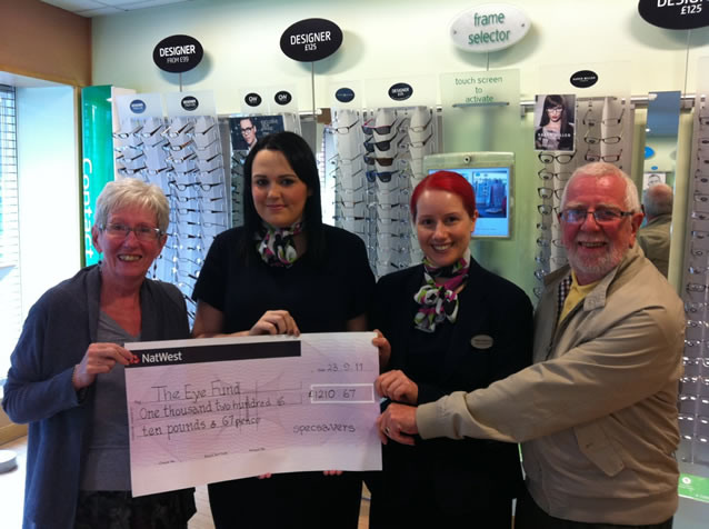 Carol and Paul receive a huge cheque from Specsavers staff.